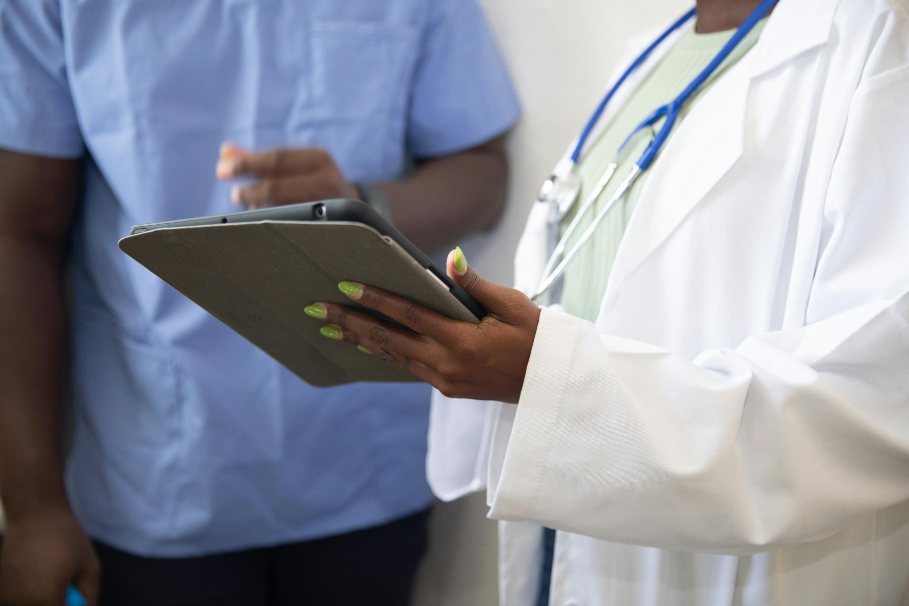 The doctor is holding a tablet in his hands, showing information to the patient. The doctor is holding a tablet in his hands, showing something to the patient.